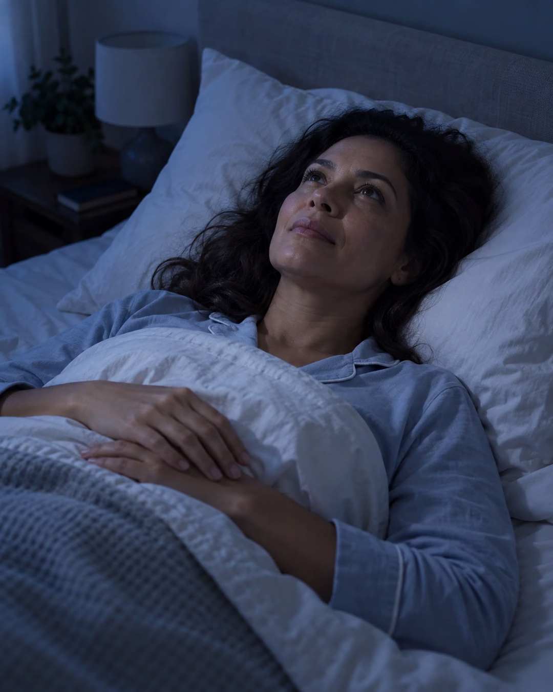 Mulher acordada na cama durante a noite olhando para o teto, representando insônia e distúrbios do sono